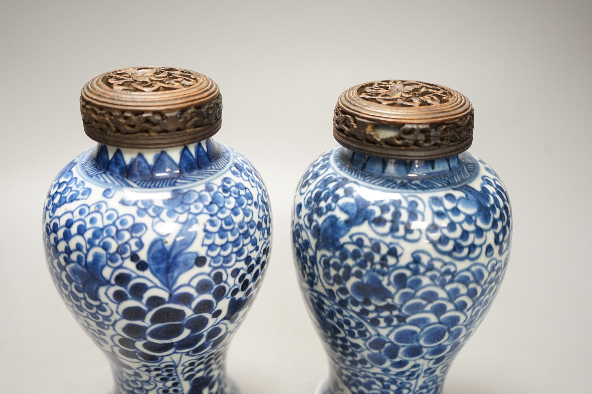 A pair of Chinese blue and white 'phoenix' vases, Kangxi, associated wood covers, 19cm including covers